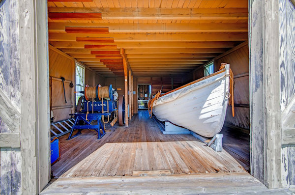 Inside of Chicamacomico Life-saving Station. Shows an old white woodedn row boat and some rescue equipment 