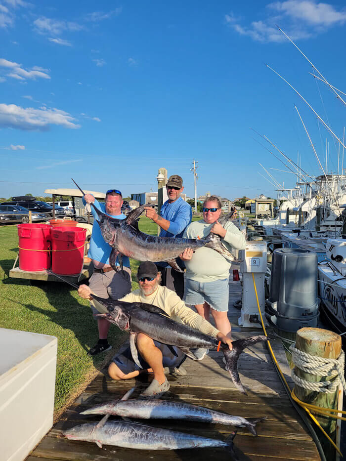 Guys holding 2 sword fish and 2 wahoo on the dock after an offshore fishing Charter