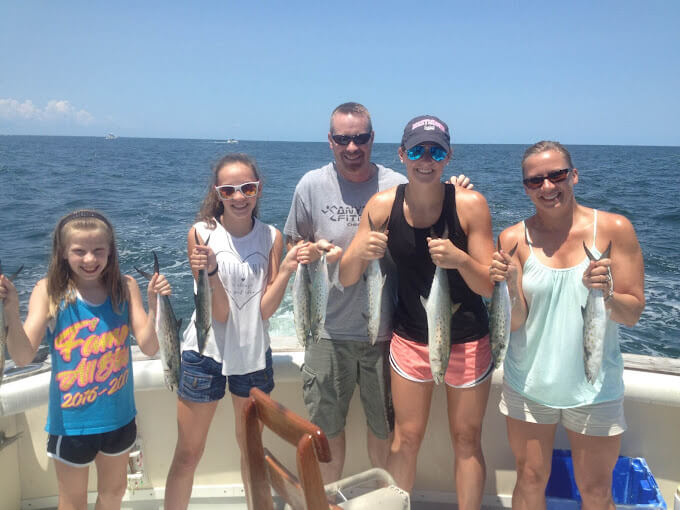 Family all holding spanish mackerel on a sunny inshore half day charter on the boat