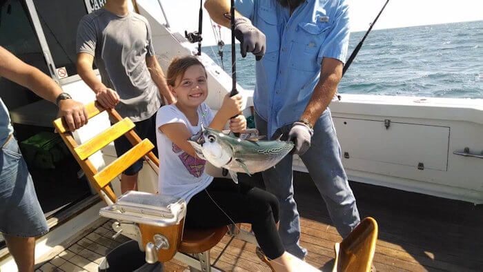 Little girl smiling after reeling in a binito tuna on a fishing charter